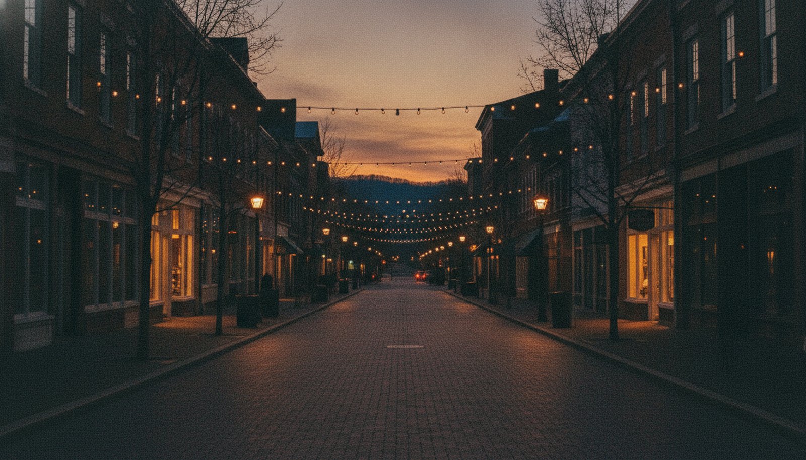 A Charlottesville downtown mall at dusk, string lights over a brick pedestrian street