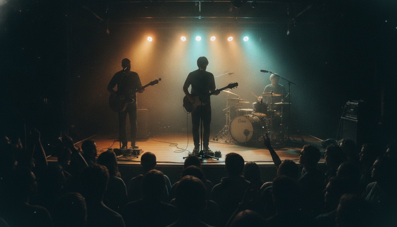 A three-piece soul-roots band in silhouette on a small stage lit amber and teal